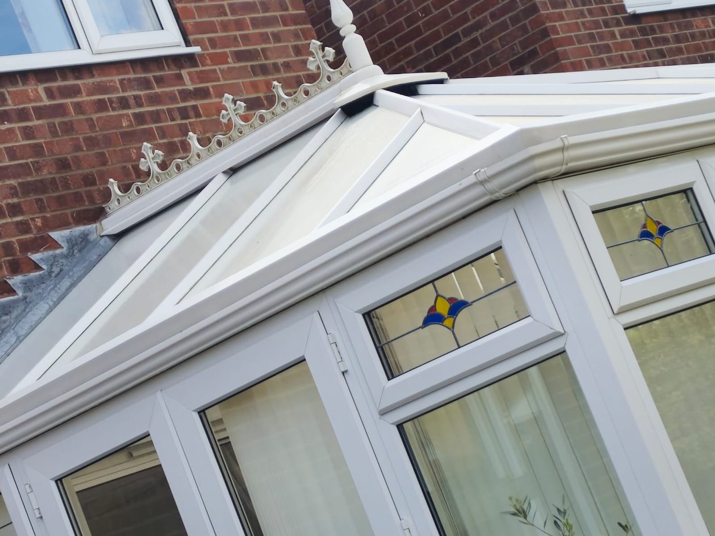 Clean conservatory roof with white framework and decorative finial