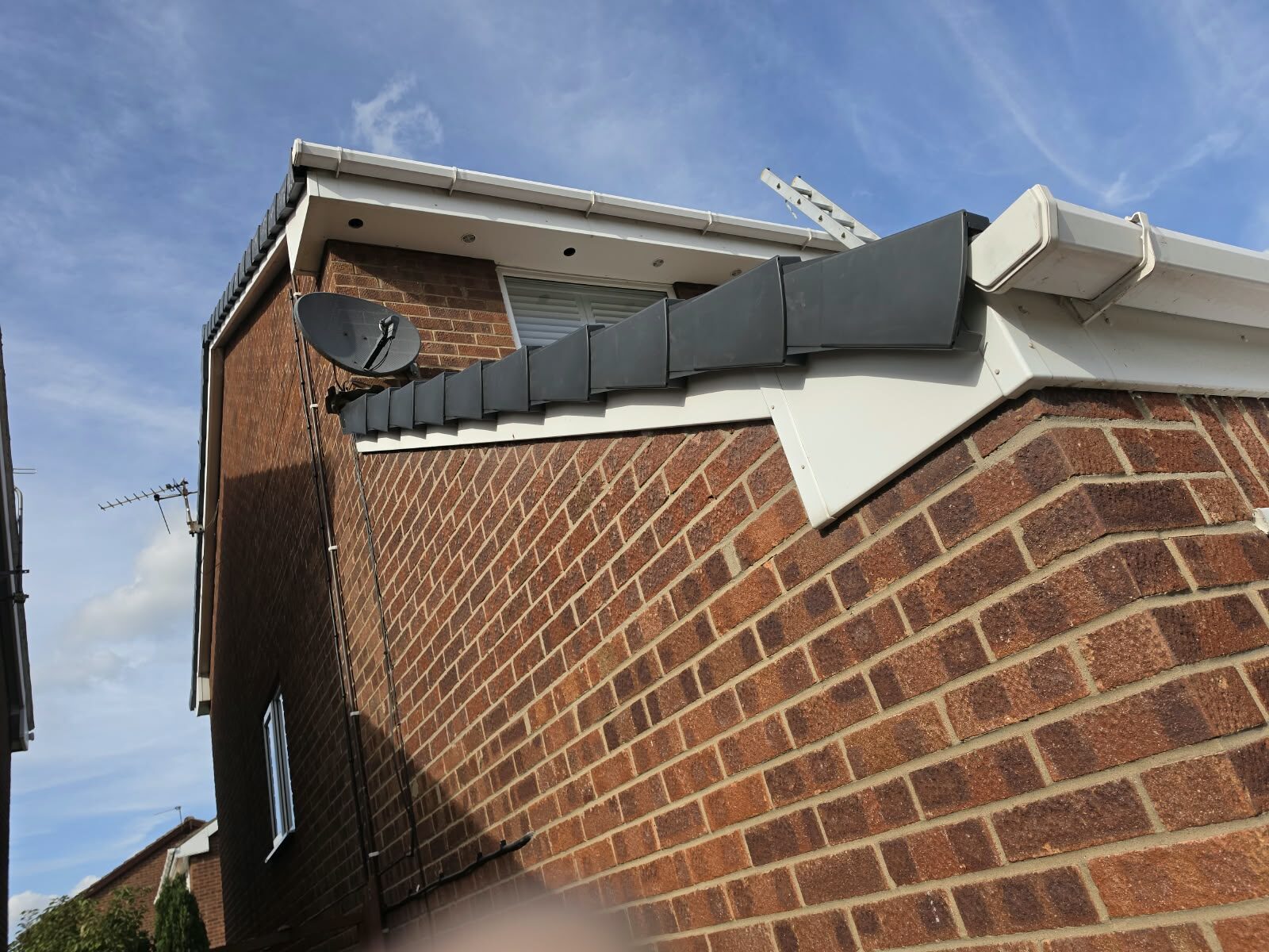 Grey dry verge end caps fitted along a gable edge with new white fascia on a house in Doncaster