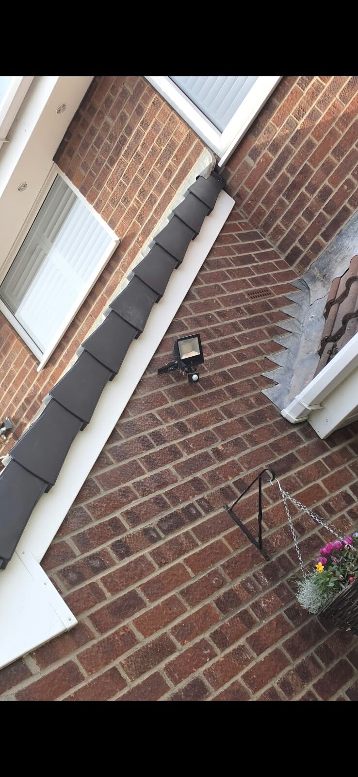 Dry verge caps fitted along a small gable roof edge above a front door with white fascia