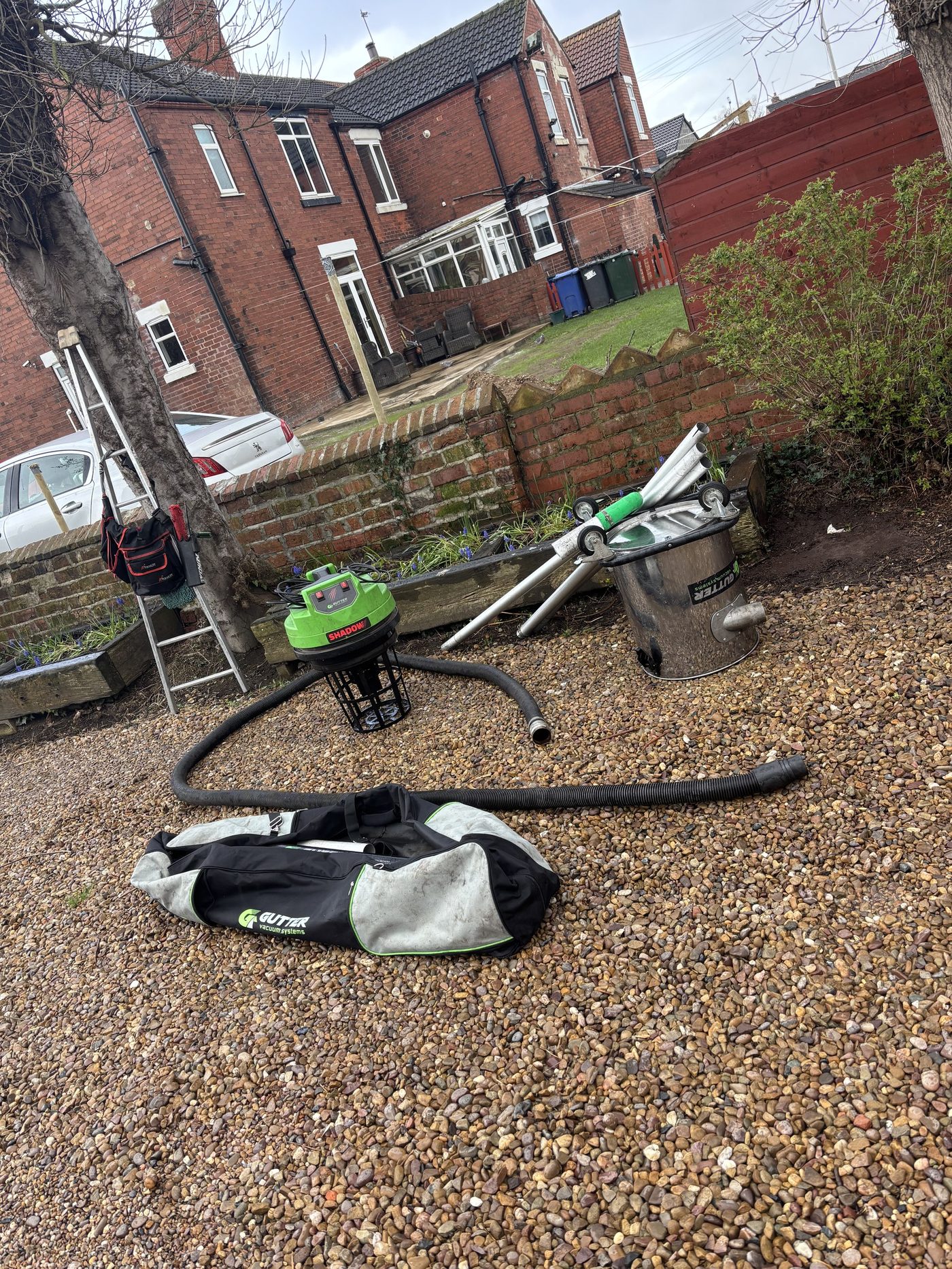Full gutter cleaning equipment laid out, vacuum, poles, ladder and collection bag